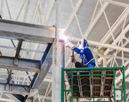 Steel fabrication worker with sparks flying during welding process