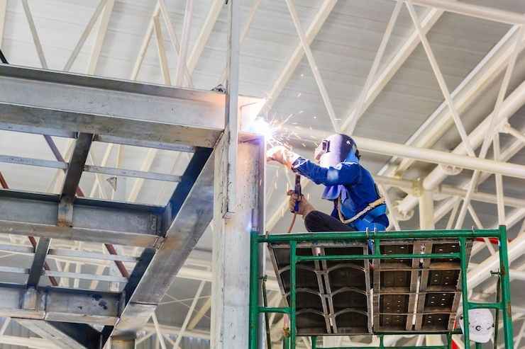 Steel fabrication worker with sparks flying during welding process